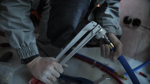Worker connecting blue hose with pliers