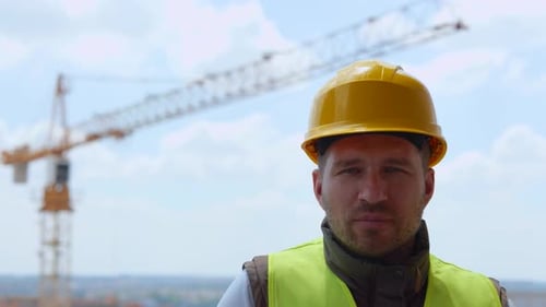 Smiling Male Architect Wearing Helmet and Posing Outdoor at Camera