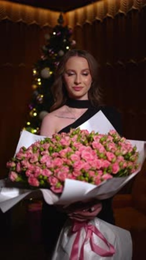 Young Woman Holding Roses near Christmas Tree