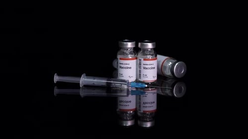 Vaccine vials and syringes on black surface