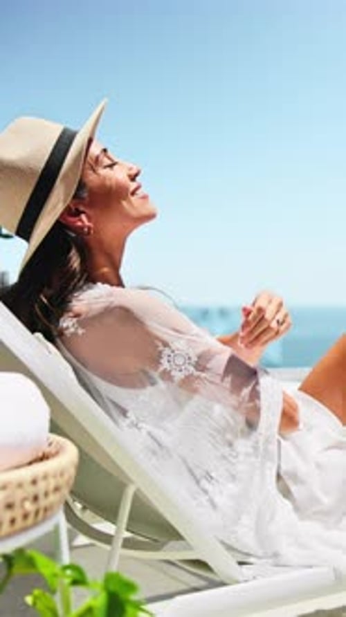 Femme prenant un bain de soleil et souriant avec une chaise longue pour les vacances, se reposer et se détendre pour un voyage ou une pause