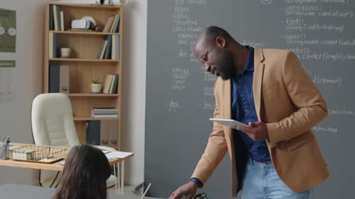 Un enseignant de sexe masculin quitte le tableau pour aider les élèves