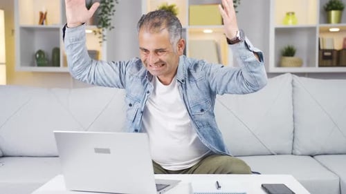 Man closing laptop with angry expression.