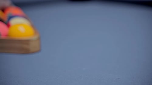 Billiard player hands with gloves moves and levels the pyramid of balls foward. Play American pool.