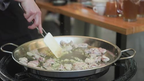 Cook Prepares Chicken in Large Paella Pan
