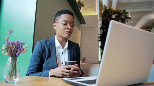 African American female holds an online meeting uses a laptop for a video call, works in a cafe,