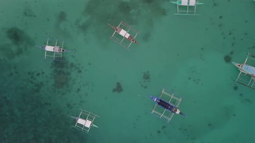 Boracay, de nombreux bateaux ancrés sur des eaux cristallines turquoises, coraux visibles. Montée aérienne lente