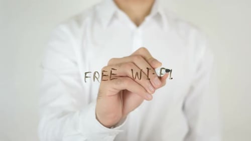 Person Writing 'Free WiFi' on Glass