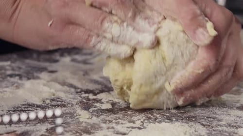Hands Kneading Dough on Floured Wooden Surface