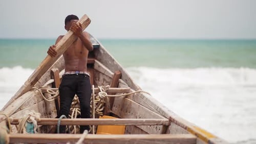 African teenage fisherman rowing canoe at sea