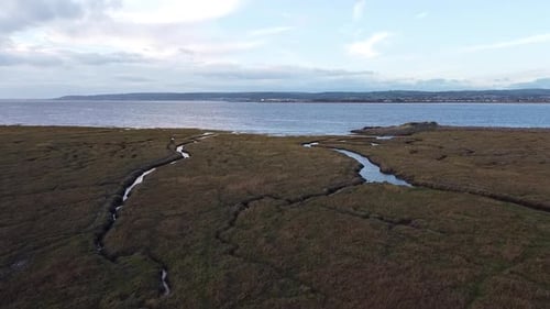 Drone shot of a salt marsh at high tide, slowly pushing in toward the sea.