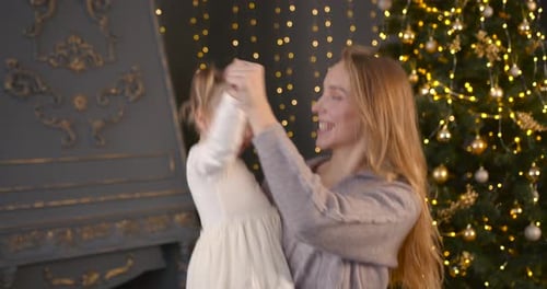 Young Woman Holding Little Daughter Near Christmas Tree