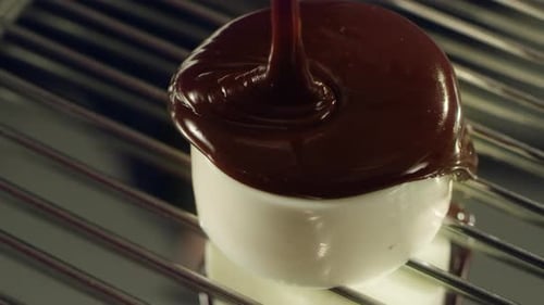 Liquid chocolate spilling on panna cotta creating delicious dessert in slow motion