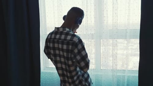 Young Adult Dancing to Music by Window