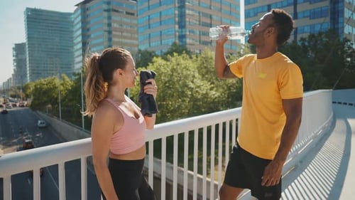 Athletic Man and Woman Drinking Water in City