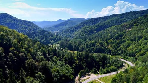Serene mountain valley with winding road. Lush green mountains surround
