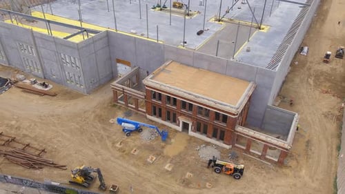 Construction of a huge warehouse using an historical structure as the entrance - aerial pull back re
