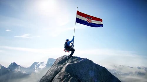 Alpiniste tenant le drapeau de la Croatie au sommet de la montagne