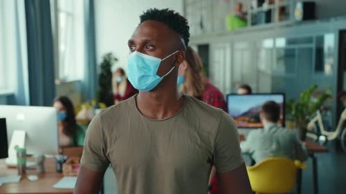 A Man in a Face Mask is at a Modern Office Highlighting Health Safety During Work