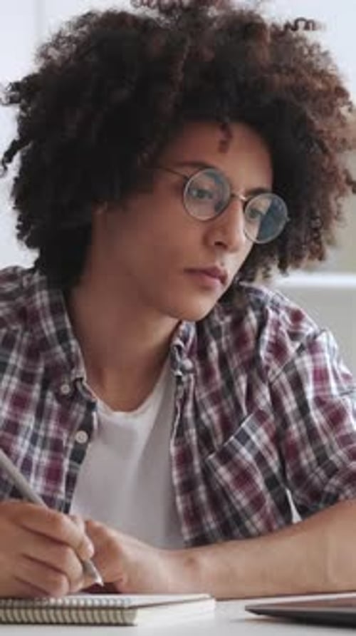 Young Adult Studies and Writes in Notebook