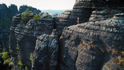 Woman stands on a high observation point overlooking the valleys and hills of Schrammsteine Elbe San