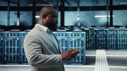 Technician Working in High Tech Server Hub Analyzing Data on Tablet