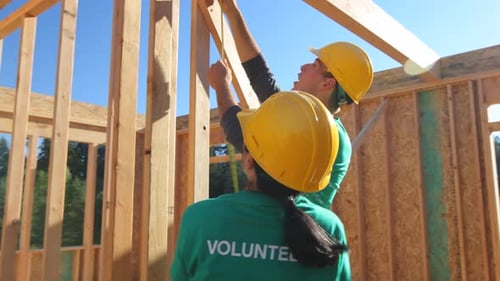 Volunteers Measure Wood Beam at Construction Site