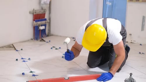 Construction Worker Installing Tile Flooring in Home
