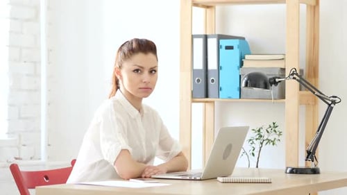 Young Woman Looks Up From Laptop at Desk