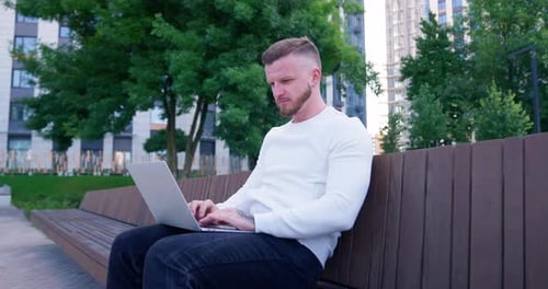 Geschäftsmann spielt Computer im Stadtpark