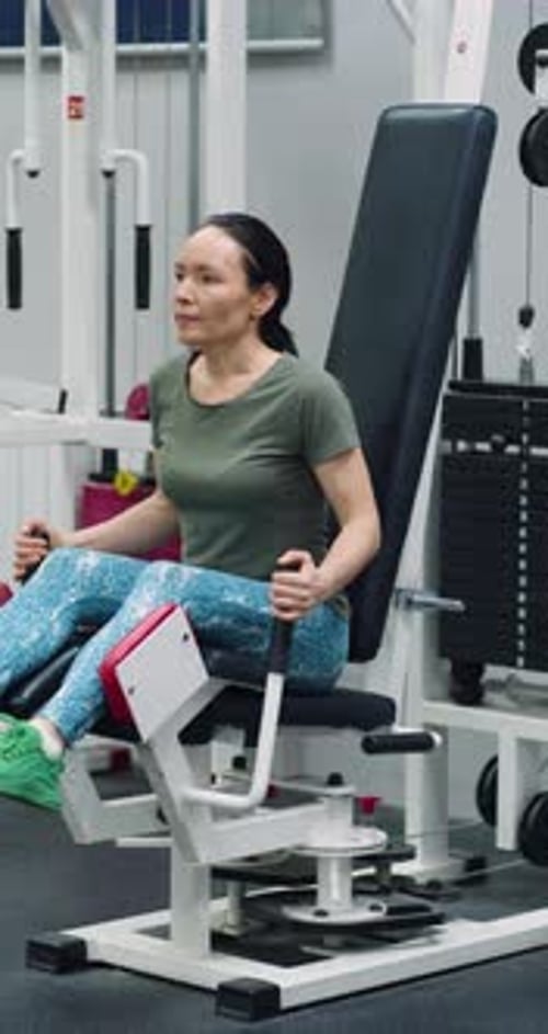 As extensões das pernas têm como alvo as pernas enquanto a mulher se exercita com determinação