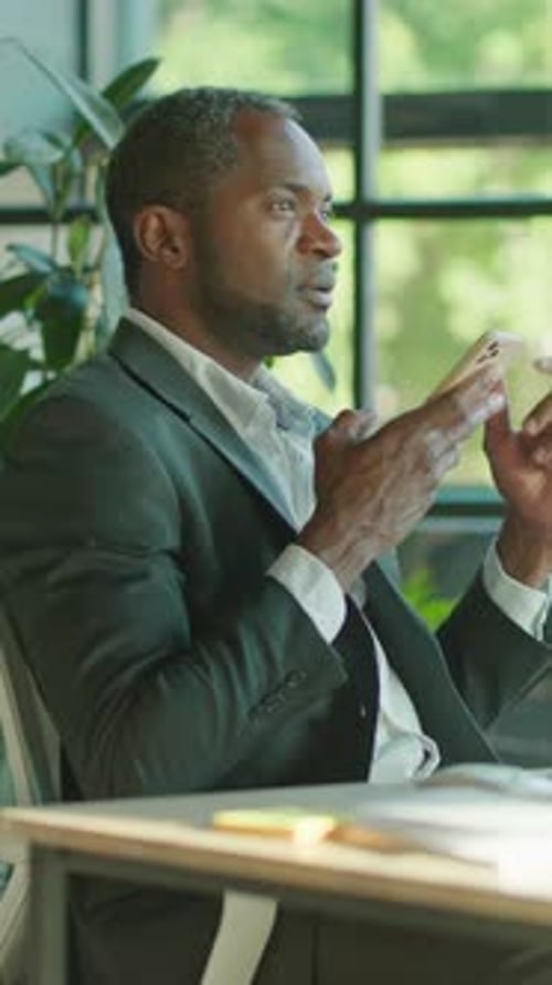 A Businessman is Actively Engaged in His Work While Using a Smartphone in a Modern Office Setting