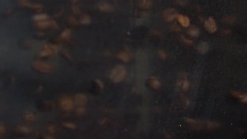 Geröstete Kaffeebohnen fallen vor dunklem Hintergrund