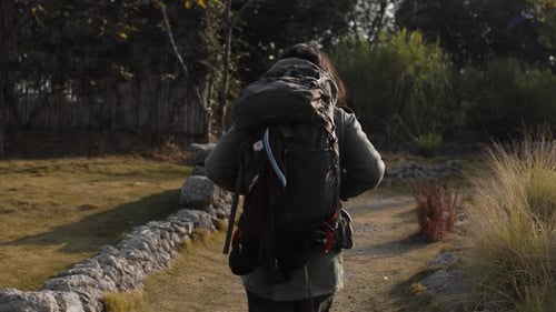 Hiker walking a scenic trail in nature with a backpack, daytime outdoor adventure