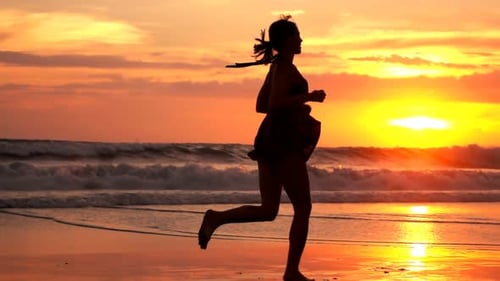 Woman Running on Beach at Sunrise for Fitness
