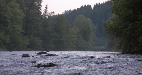 Water flows down the river at dawn in the mountain landscape between stones