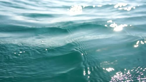 Die Meerwasseroberflächenkamera fliegt über das ruhige azurblaue Meer mit vulkanischen Felsküsten im Hintergrund