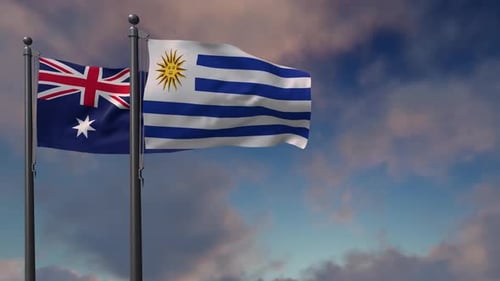 Australia and Uruguay Flags Waving on Poles against Cloudy Sky