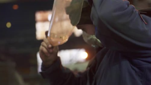 A Skilled Worker Carefully Analyzing Materials Under Challenging Low Light Conditions in a Factory