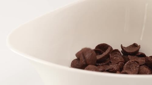 Chocolate Cereal Falling Into White Bowl