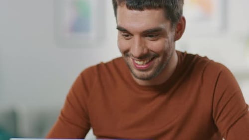 Smiling Man Working on Laptop at Desk