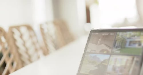 Biracial man using tablet with home security camera views on screen