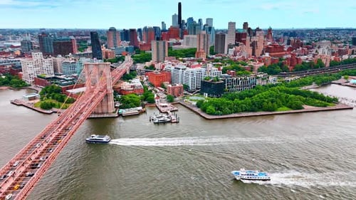 Boats move by the East River heading to the Brooklyn Bridge of New York, USA.