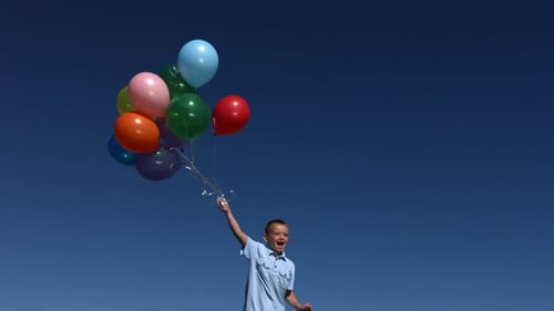 Joyful Child Jumps with Balloons Against a Blue Sky
