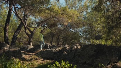 A Young Female Tourist Comes Out of the Forest Along a Stone Ridge