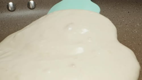 I turn the pancake over in a frying pan with a silicone spatula. extreme close-up.