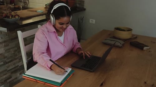 Woman Studies Using Laptop and Notebook at Home