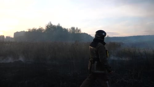 Firefighter Walking Through Smoky Burned Field