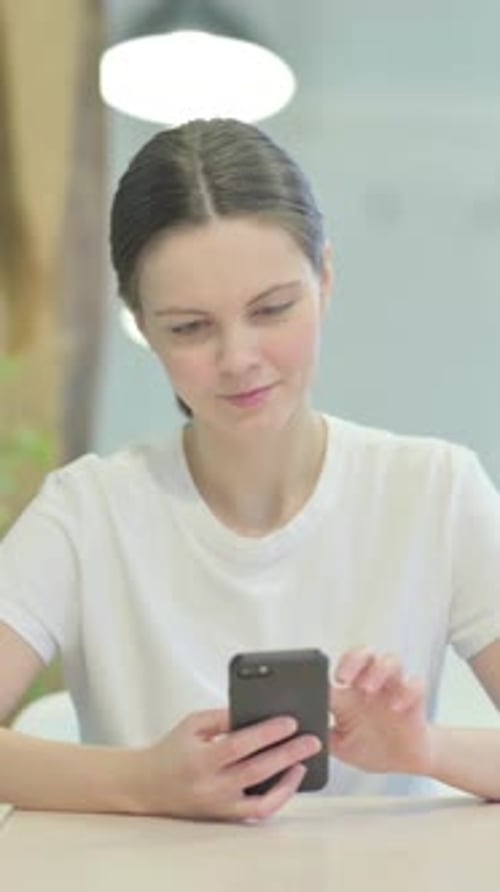 Young Woman Using Mobile Phone Indoors in Portrait Mode