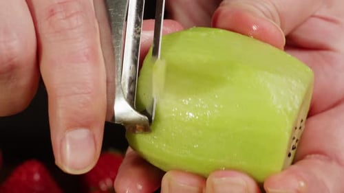 Hands Peel a Kiwi with Fruit Peeler